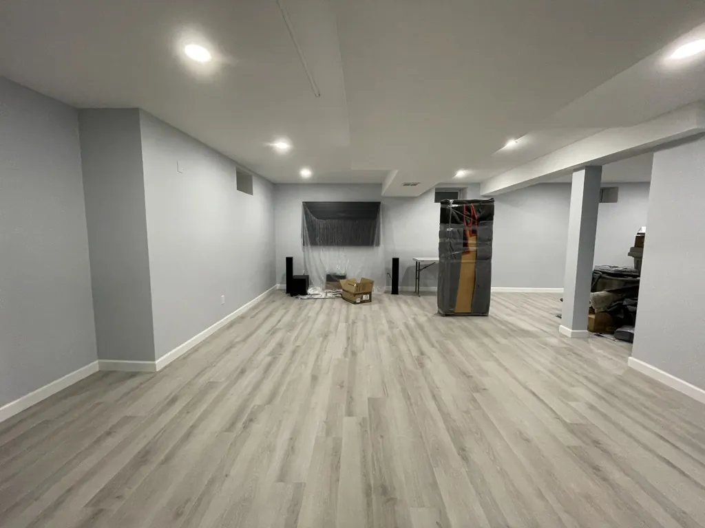 Finished basement with light plank flooring, painted walls and recessed ceiling lights