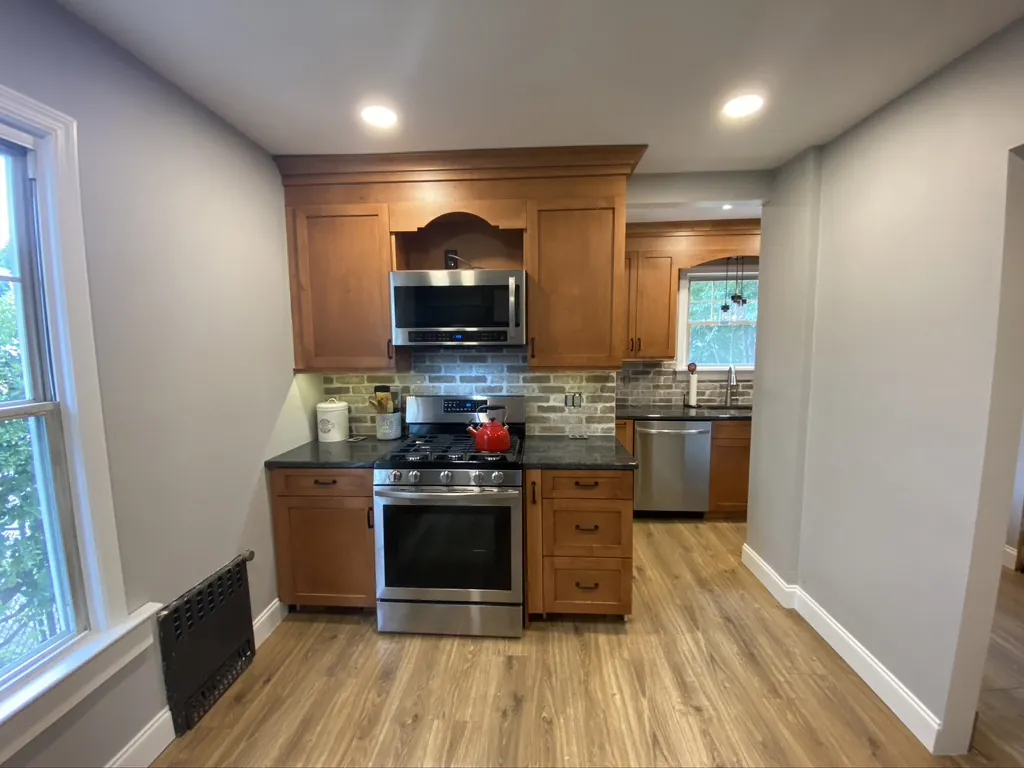 Finished kitchen with wood cabinets, a tile backsplash, stone counters and stainless appliances